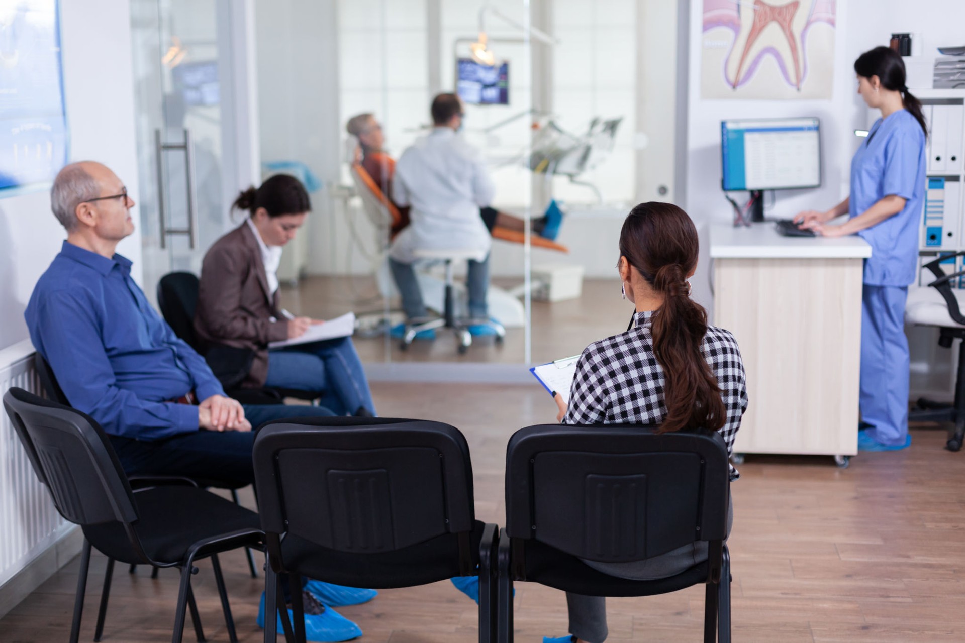 Crowded stomatology waiting area with people filling form